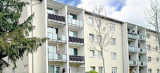 Mehrfamilienhaus mit Balkonen, die Balkonkraftwerke am Geländer befestigt haben